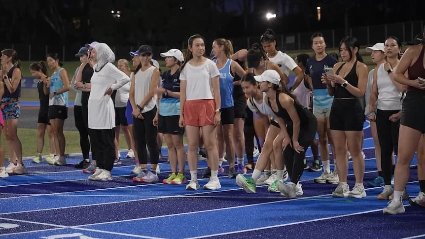 a group women at a race track stand at the starting line
