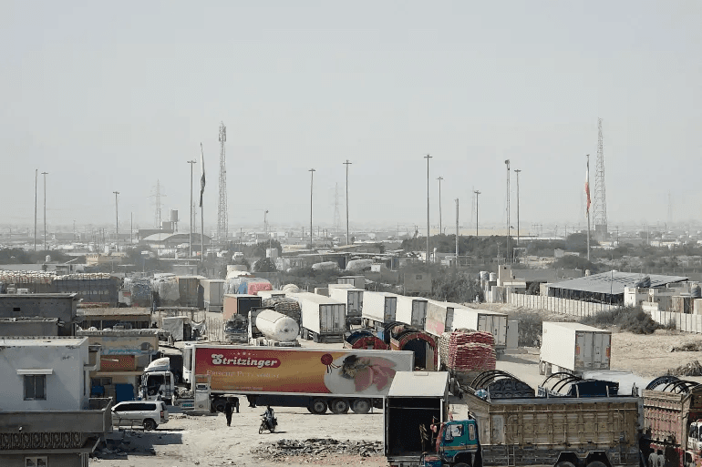 National flags of Pakistan and Iran stand beside cargo trucks halted at the Gabd-Rimdan border crossing in Balochistan, Pakistan, on October 21, 2026, following the suspension of cross-border trade.